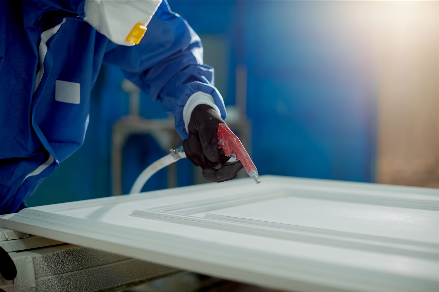 Spray technician applying a professional finish to kitchen cabinet panels